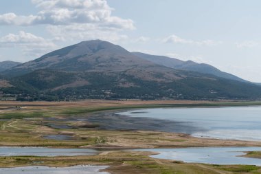 Busko Gölü yaz mevsiminde alçak su seviyeleri ve arka planda dağlarla çevrili.