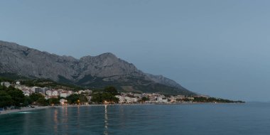 Hırvatistan 'daki Biokovo Dağı' nın altındaki Adriyatik kıyısındaki turizm beldesi Baska Voda, yazın alacakaranlıkta