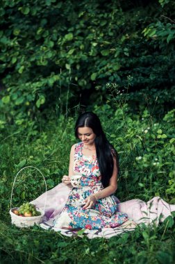 Doğada meyve çayı içen, yazın piknikte oturan ve elinde bitki çayıyla büyük sarı bir bardak tutan beyaz bir kız. Çay seremonisi. Çocukluk. Kamp yapmak. Yaz konsepti.