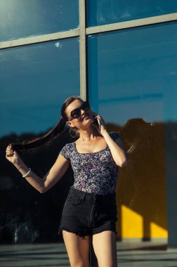 Havalı kız Tel 'de konuşuyor. Mağaza vitrininin yanında kısa şortlu güzel bir kız..