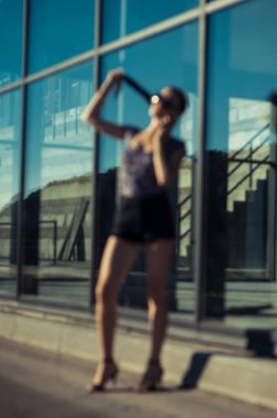 Havalı kız Tel 'de konuşuyor. Mağaza vitrininin yanında kısa şortlu güzel bir kız..