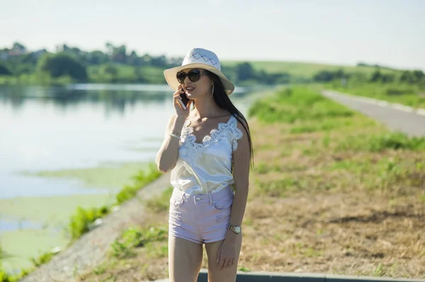 川のそばで電話で話してるクールな女の子 — ストック写真