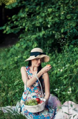 Ormandaki piknikte bir kız. Güzel bir kadın meyve yer..