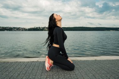 Spor kıyafetleri içinde gün batımına karşı spor egzersizleri yapan çekici bir kadın. Aktif genç kız
