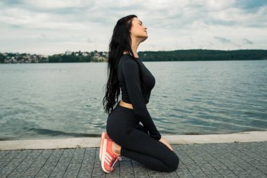 Spor kıyafetleri içinde gün batımına karşı spor egzersizleri yapan çekici bir kadın. Aktif genç kız