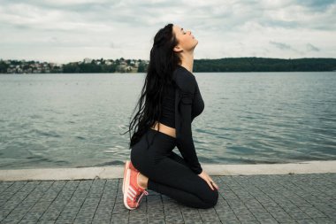 Spor kıyafetleri içinde gün batımına karşı spor egzersizleri yapan çekici bir kadın. Aktif genç kız