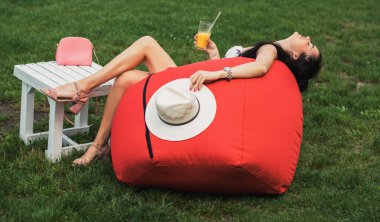 Güzel kız su kenarındaki parkta meyve suyu içiyor..