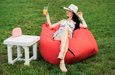 Güzel kız su kenarındaki parkta meyve suyu içiyor..