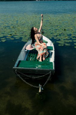 Göldeki bir teknede esmer bir kız. Güneşli bir gün.