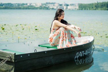 Göldeki bir teknede esmer bir kız. Güneşli bir gün.