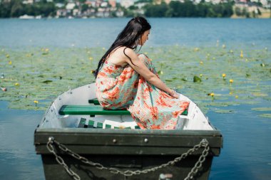 Göldeki bir teknede esmer bir kız. Güneşli bir gün.