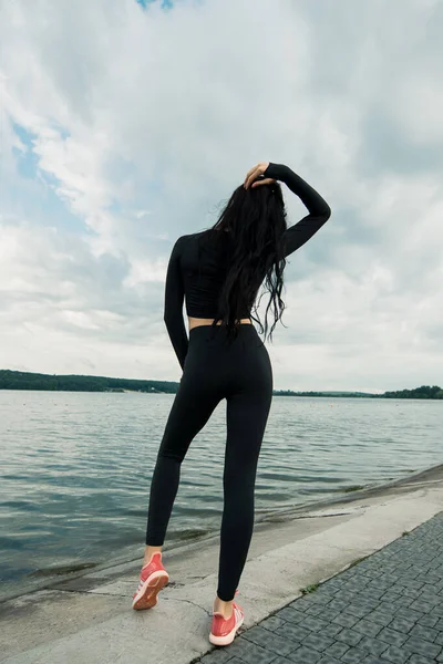 Spor kıyafetleri içinde gün batımına karşı spor egzersizleri yapan çekici bir kadın. Aktif genç kız