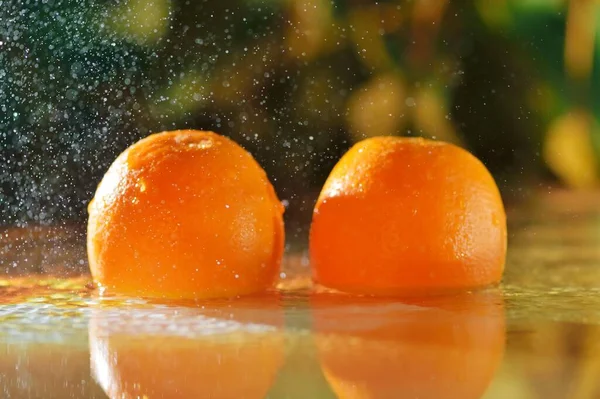 Fruits of orange fall in water with drops of water. Orange fruits are water in the nature.