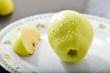 Meyveleri dilimliyorum. Masada sarı sulu elmalar var..