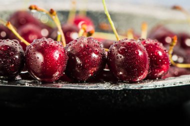 Su sıçratan kiraz siyah arkaplan.