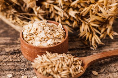 Tahta bir masanın üzerindeki yulaf lapası, yulaf ezmesi. Cömert hasat. Sağlıklı taze bir kuru yulaf yemeği. 