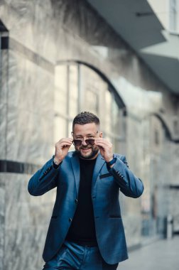 Takım elbiseli ve güneş gözlüklü şık bir adam..