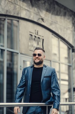 Ofisin yakınında bir adam toplantı bekliyor. Mavi takım elbiseli bir iş adamı..