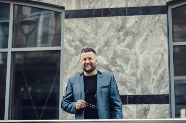 İş adamı telefonda, bir toplantıda konuşuyor. Adam el sallıyor. Yakışıklı, esmer, sakallı, gülümseyen yönetici. İş yerinde çalışıyor, telefonda konuşuyor.