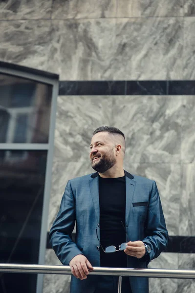 Ofisin yakınında bir adam toplantı bekliyor. Mavi takım elbiseli bir iş adamı..