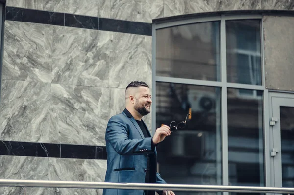 Ofisin yakınında bir adam toplantı bekliyor. Mavi takım elbiseli bir iş adamı..