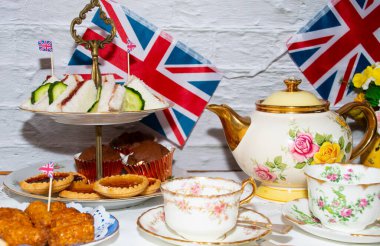 Platinum Jubilee  vintage  tea part  celebrations  with flags   of the  Union Jack   and  party  food  and  vintage  tea set  clipart