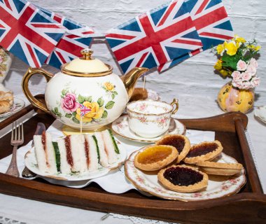 Platinum Jubilee  vintage  tea part  celebrations  with flags   of the  Union Jack   and  party  food  and  vintage  tea set  clipart