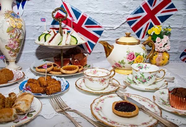 Platinum Jubilee  vintage  tea part  celebrations  with flags   of the  Union Jack   and  party  food  and  vintage  tea set 