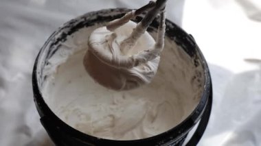 Macunu karıştırıcıyla yoğur, yoğurmaya başla, yukarıdan yakın çekim. Macunu örüyorum. Usta macunu bir kovada karıştırıcı ile karıştırıyor. DIY ev onarımı, iç yenileme