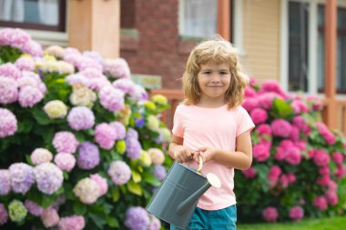 Çocuk, anne babaya su bidonuyla yardım ediyor. Bahçe malzemeleri.