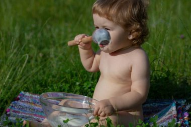Otların üzerinde oturan komik bebek yemek için tahta kaşık tutuyor..