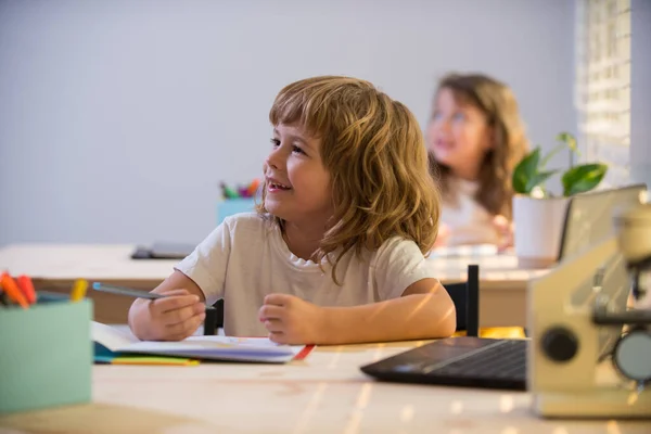Vissza a suliba. Boldog mosolygó diákrajzot az asztalnál. Egy gyerek az általános iskolából az osztályteremben. az ősz első napja. Oktatás és tanulás gyerekeknek. — Stock Fotó