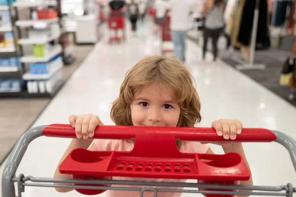 Закрыть портрет ребенка с корзиной покупок продуктов питания в продуктовом магазине. Клиенты семьи покупают продукты в супермаркете. Смешное детское лицо. — стоковое фото