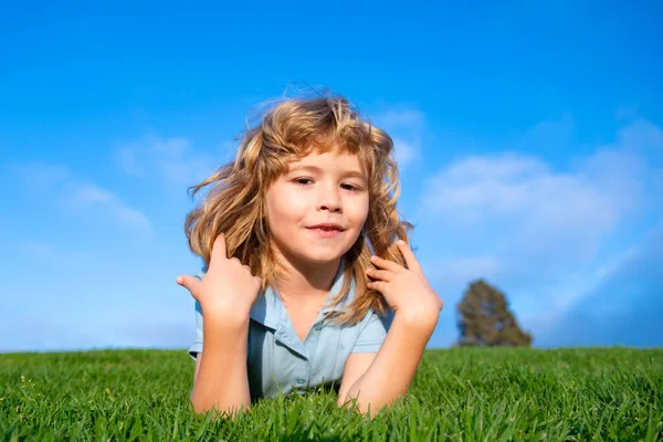 Portret van een lachend jongetje op groen gras. glimlachende jongen hebben plezier buiten in de lente tuin. — Stockfoto