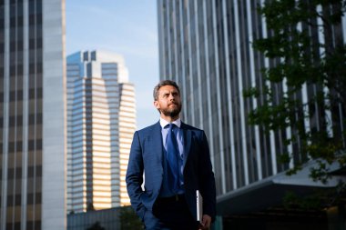 İş adamının elinde dizüstü bilgisayar vardı. İş yerinin yakınında duruyordu..