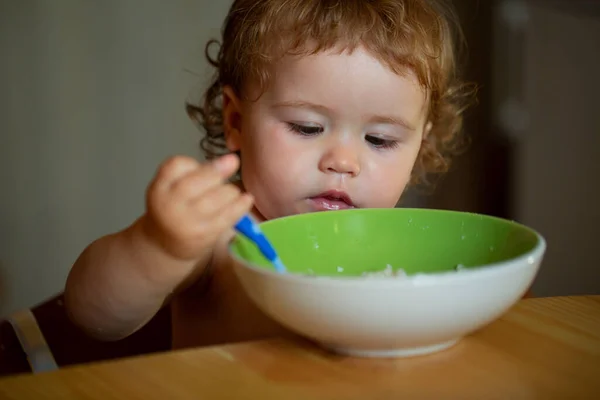 Portret van grappige kleine jongen eten van bord houden lepel close-up. — Stockfoto