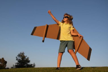 Çocukların lideri ve kazananı, başarı başlar. Heyecanlı çocuk parkta oyuncak jet kanatlı süper kahramanla oynuyor. Mavi gökyüzünde tatil gezisi.