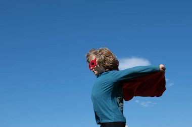 Küçük çocuk süper kahramanı oynuyor. Gökyüzündeki arka plandaki çocuk.