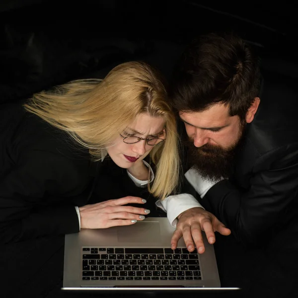 Porträtt av ett affärspar tittar på laptop tillsammans på mörka kontoret. — Stockfoto