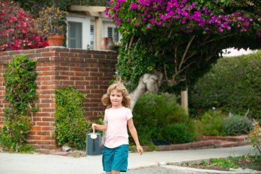Bahçesinde su kovası olan bir çocuk. Tatlı çocukluk. Bahçede çiçekleri sulayan mutlu çocuk.