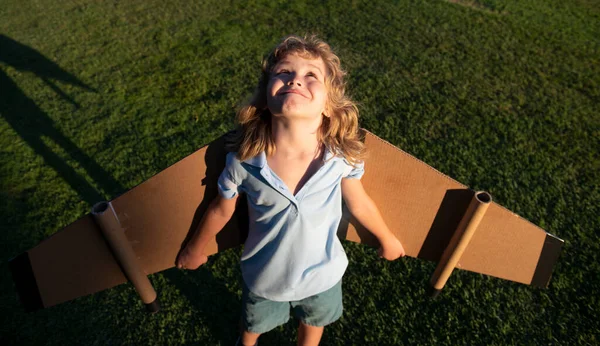 Barnpojken leker med flygplansvingar. Dröm om att bli pilot. Superhjälte flyger. — Stockfoto