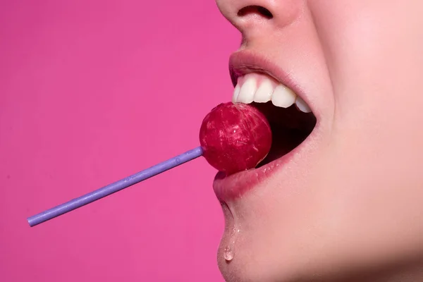 口の中でピンクのリップグロスを持つ女性の唇を閉じます赤いロリポップキャンディー。ロリポップ唇女性の顔. — ストック写真