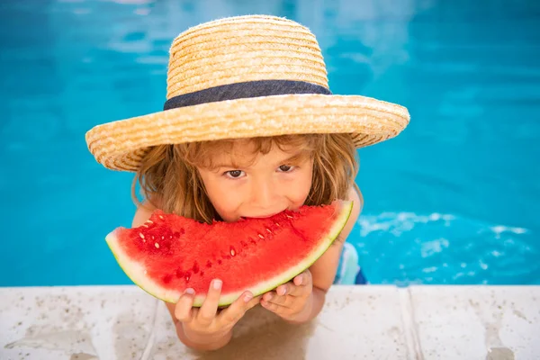 Un niño gracioso juega en la piscina. El niño come una sandía dulce, disfrutar del verano. Niñez despreocupada. — Foto de Stock