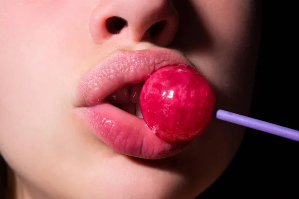 Flicka med sexig mun äta Chupa Chups närbild. Kvinnliga läppar suger klubba. Oralsex avsugning koncept. Kvinna håller klubba i munnen, närbild. Röda läppar, sensuell och sex shop koncept. — Stockfoto