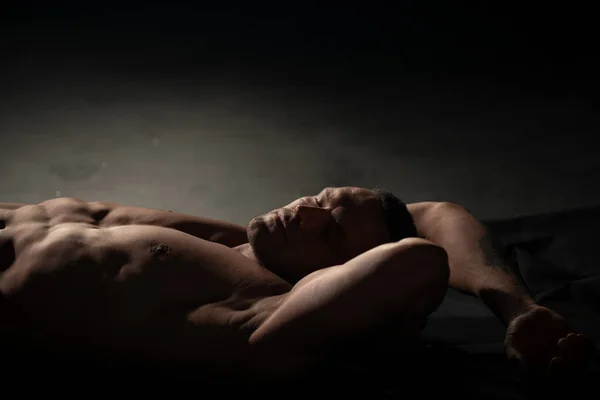 Sexy hombre musculoso desnudo con abdominales sixpack acostado en la cama. Atractivo joven gay. Bienestar, concepto de bienestar. — Foto de Stock