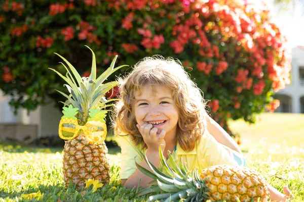 Menino segurando um abacaxi posando fundo natureza verão com espaço de cópia. Frutos saudáveis para o conceito de crianças. — Fotografia de Stock