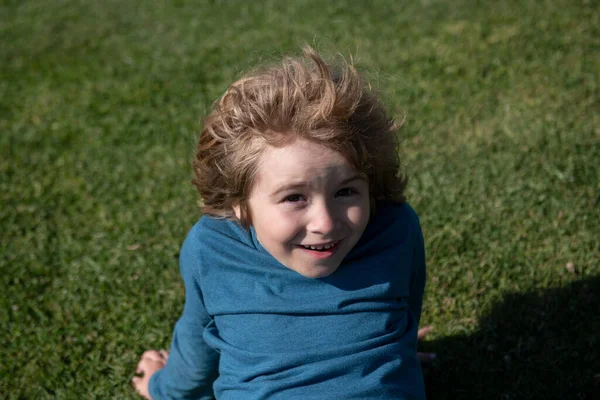 Närbild porträtt av glada barn på gräs i parken. Söt glad liten pojke unge. Närbild porträtt av roliga lilla barn pojke. — Stockfoto