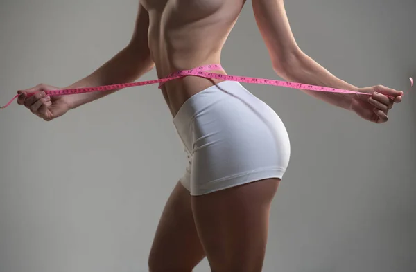 Vrouw taille met tape, gewichtsverlies. Vrouwelijk model lichaamsverzorging. Vrouw die de meter vasthoudt met handen en taille. — Stockfoto