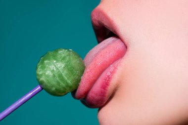 Dudaklarını yalıyor. Lolipop yalayan bir kadın, sanat afişi, lolipoplu kırmızı dudaklar. Lolli pop ile seksi kırmızı kadın ağzı ve dili. Tasarım için resim baskısı.