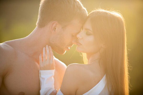 Sensual kiss. Man kissed tender woman at sunset. Sensual portrait of young couple in love. Loving couple embracing and kissing.